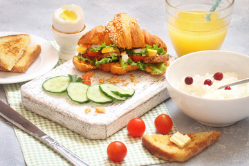 Breakfast with croissant sandwich, rice, Casas berries, boiled egg, toast with butter, orange juice and vegetables