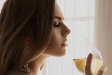 young woman drink champagne near the window