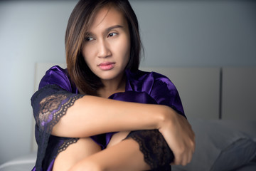 Portrait of a young woman in purple satin nightwear suffering from insomnia