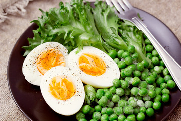 Organic ingredients for a salad with lettuce, frozen peas and eggs on rustic background. Healthy food, or diet nutrition concept.