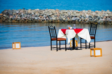 Table with chairs served for couple on seascape background