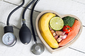 Food and healthy heart diet concept with blood preasure guage on white planks
