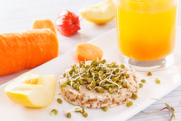 Useful breakfast from natural products. Sprouted grains on a puffed wheat cake. Fresh apples and carrots, fresh juice. Healthy diet food