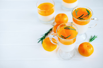 Tangerine panna cotta dessert with rosemary in wineglasses