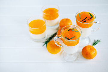 Tangerine panna cotta dessert with rosemary in wineglasses