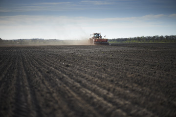Fototapeta premium Red tractor with sowing machine on a ploughed field