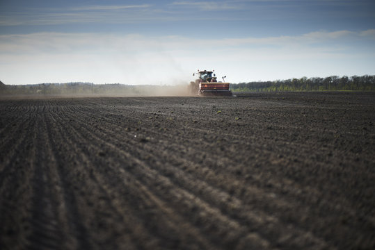 Red tractor with sowing machine on a ploughed field
