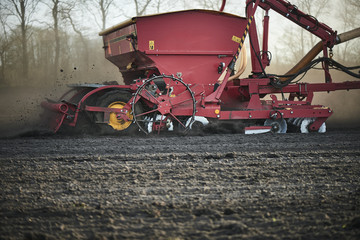Red tractor with sowing machine on a ploughed field