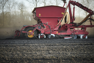 Red tractor with sowing machine on a ploughed field