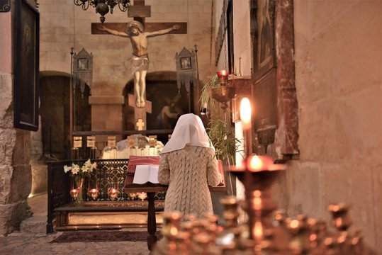 nun praying in a church infront of jesus christ cross