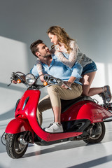 Plakat side view of stylish young couple on red scooter looking at each other