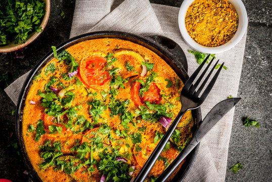 Indian food recipes, Masala Omelette with fresh vegetables - tomato, hot chili pepper, parsley, dark stone background, copy space top view