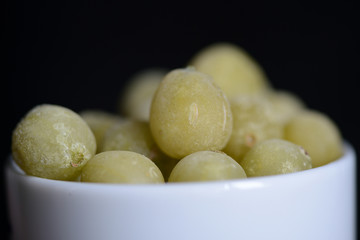 Frozen gooseberries on a dark background close up