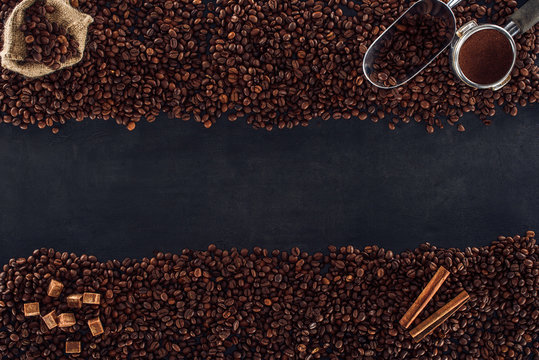 top view of roasted coffee beans, sackcloth, coffee tamper and scoop. brown sugar and cinnamon sticks on black © LIGHTFIELD STUDIOS