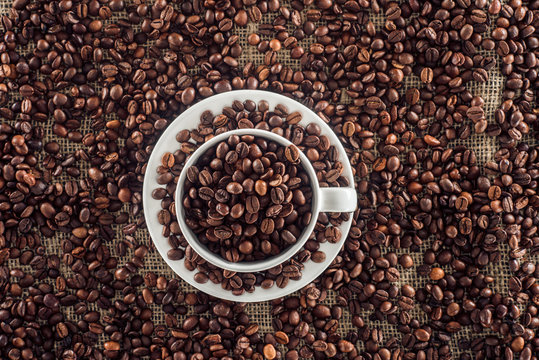 top view of coffee cup and roasted coffee beans on sack clothes