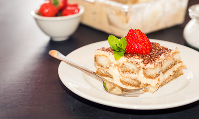 Homemade tiramisu cake decorated with strawberries Italian cuisine, Selective focus