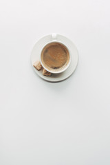 top view of cup of aromatic coffee with saucer and brown sugar isolated on white