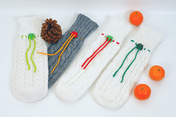 Four empty knitted bottle covers placed on a white background