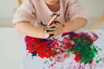 Little asian girl painting with paintbrush and colorful paints