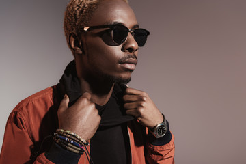 Stylish young african american man straightens his jacket isolated on light background