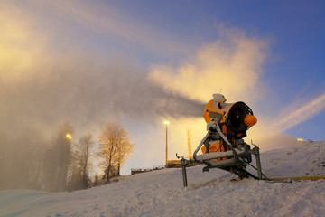 Snow cannon prepares ski slope early in the morning