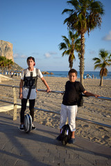 Obraz premium Young boys are riding MonoWheels, Elecrtic Scooters enjoying the ride on a beach promenade