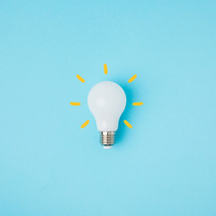 close up view of white light bulb with yellow lines isolated on blue