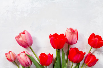 Fototapeta premium Background Valentine's Day or wedding. Red and pink tulips bouquet on a gray stone background. The apartment was lying. Top view with copy space.
