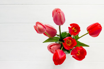 Fototapeta premium Background wedding or Valentine's Day. Red and pink tulips bouquet on a wooden table. The apartment was lying. Top view with copy space.