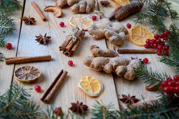 Obraz na płótnie Canvas Traditional spices for mulled wine or Christmas bakery dried orange, anise, cinnamon, ginger, viburnum on wooden background. Decorated with Christmas tree branches, pine cones. New year composition
