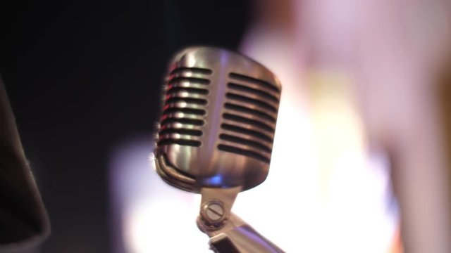 Classic retro chrome microphone over blurred bokeh circles background at night.
