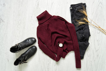 Bordeaux turtleneck, black boots, watches and ripped jeans. Spikes of wheat. Fashionable concept