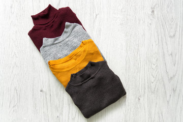 Four sweaters on a wooden background. Fashion concept.