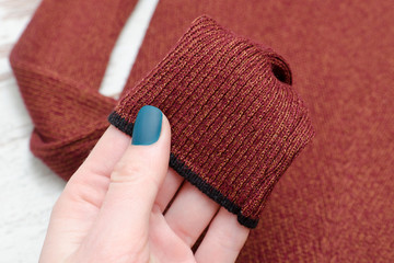 Sleeve brown sweater in a female hand. Fashionable concept. Close-up