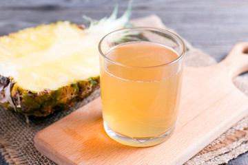 Fresh pineapple juice in a glass on a cutting board