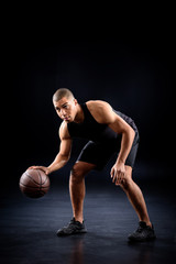 african american basketball player bouncing ball on black