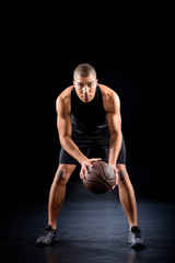 concentrated african american basketball player with ball on black