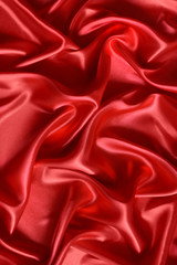 Close up of ripples in red silk fabric. Satin textile background.