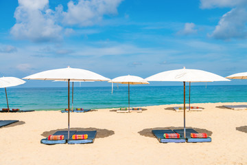 Idyllic beach relaxing concept with white parasols on sand