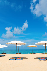 Fototapeta na wymiar Idyllic beach relaxing concept with white parasols on sand