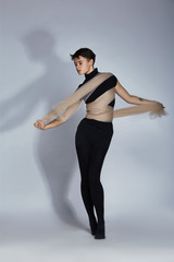 Obraz premium An unusual girl with short hair in all black with beige cloth