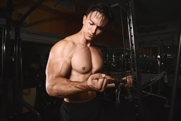 Fototapeta na wymiar Young man training on exercise machine in gym