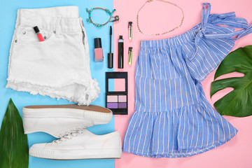 Composition with trendy clothes and tropical leaves on color background