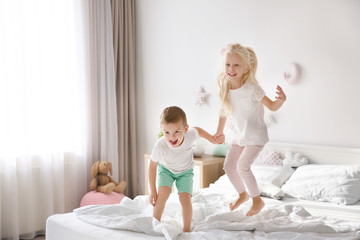 Obraz na płótnie Canvas Cute little children jumping on bed at home