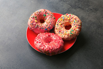 Plate with yummy colorful donuts on grey background