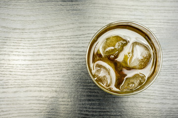 A glass of whiskey and ice on the table. View from above.