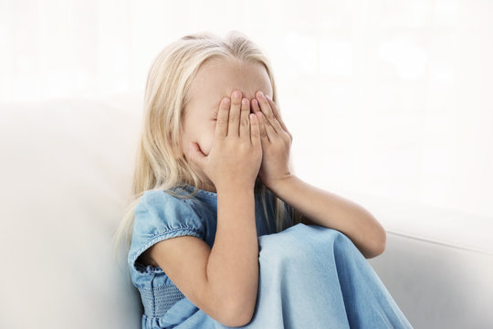 Helpless little girl crying indoors. Child abuse concept