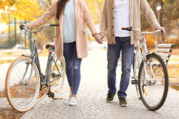 Obraz premium Young couple walking with bicycles in park
