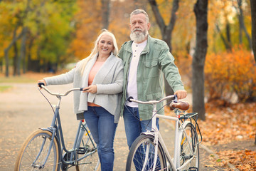 Obraz premium Senior couple walking with bicycles in park