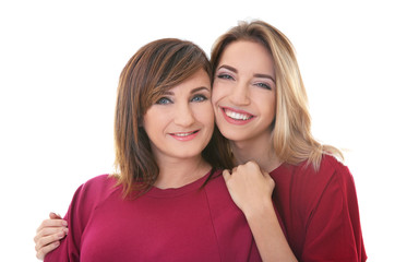 Attractive young woman with her mother in matching dresses on white background